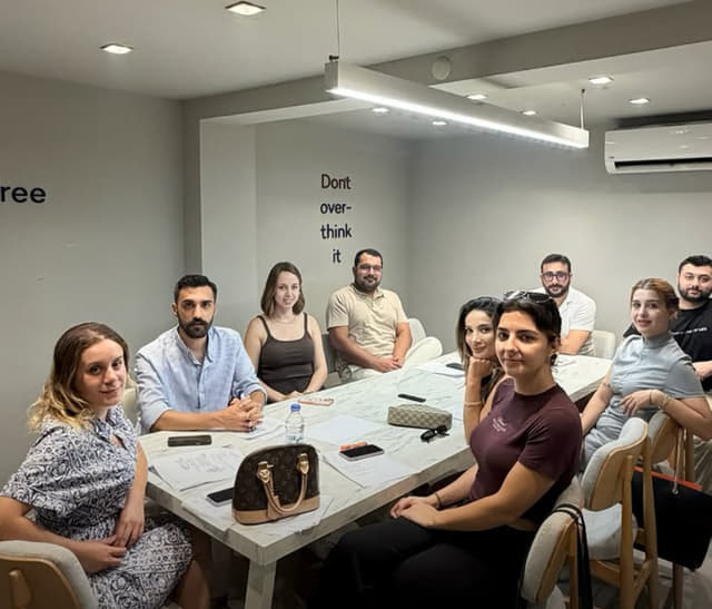 Dernek yönetim kurulu üyeleri uzun bir masanın çevresinde toplantı yapıyor.